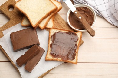 Photo of Tasty chocolate butter, slices of bread and knife on light wooden table, flat lay