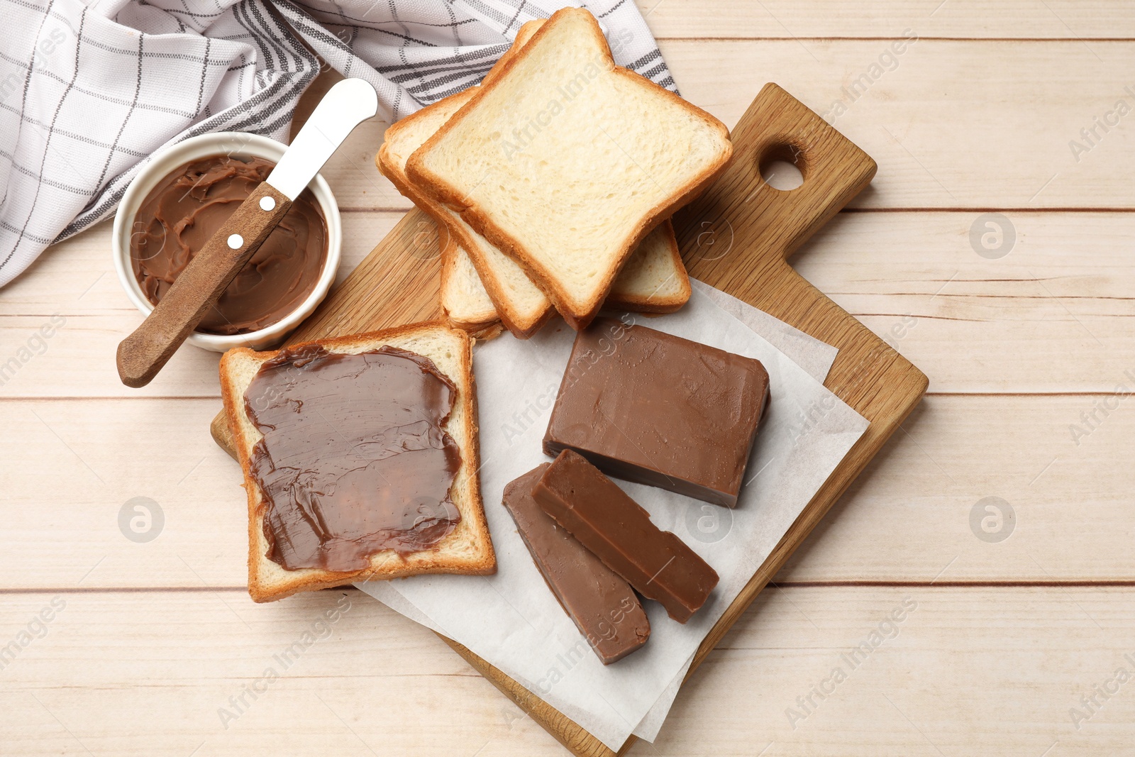 Tasty chocolate butter, slices of bread and knife on light wooden table, flat lay Photo of Tasty chocolate butter, slices of bread and knife on light wooden table, flat lay