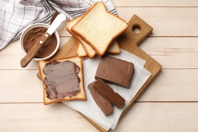 Photo of Tasty chocolate butter, slices of bread and knife on light wooden table, flat lay