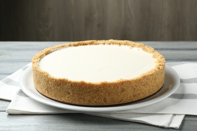 Photo of One tasty cheesecake on grey wooden table against brown background, closeup