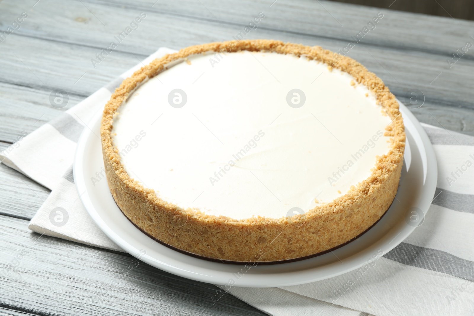 Photo of One tasty cheesecake on grey wooden table, closeup