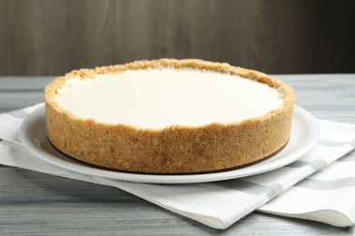 Photo of One tasty cheesecake on grey wooden table against brown background, closeup
