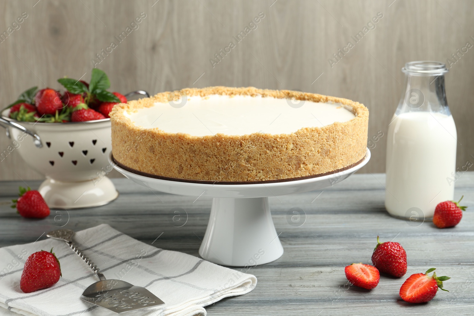 One tasty cheesecake, strawberries and milk on grey table against wooden background, closeup Photo of One tasty cheesecake, strawberries and milk on grey table against wooden background, closeup