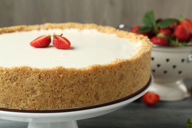 Photo of One tasty cheesecake with strawberry on grey table, closeup