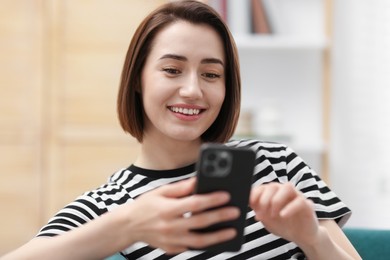 Photo of Beautiful woman using modern smartphone at home