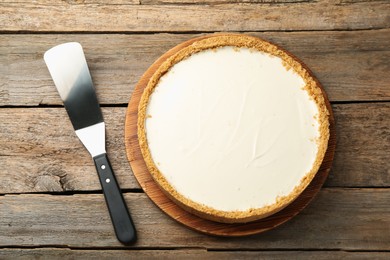 Photo of One tasty cheesecake and server on wooden table, flat lay