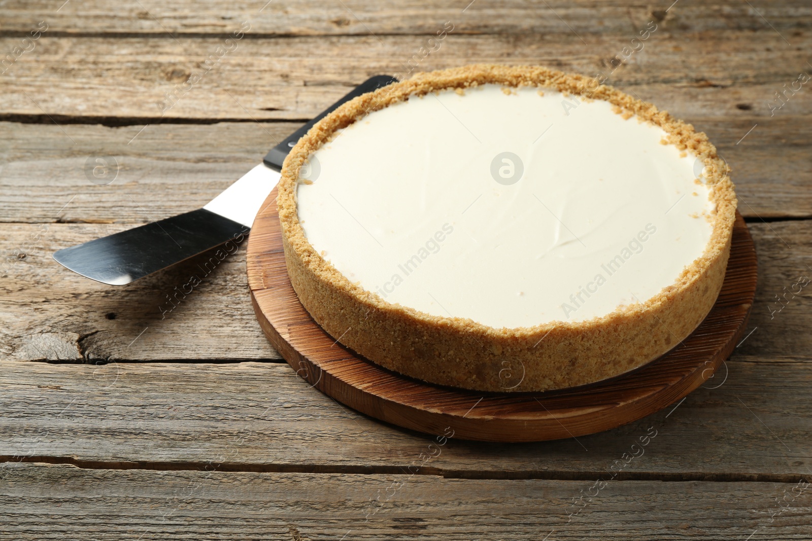 Photo of One tasty cheesecake and server on wooden table, closeup