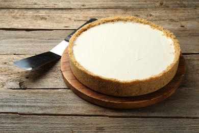 Photo of One tasty cheesecake and server on wooden table, closeup
