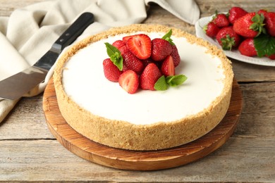 Photo of Tasty cheesecake with strawberries and mint on wooden table, closeup