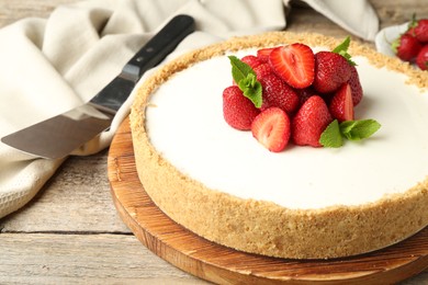 Photo of Tasty cheesecake with strawberries and mint on wooden table, closeup