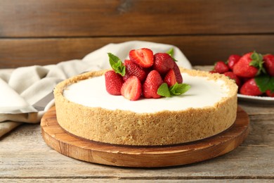 Photo of Tasty cheesecake with strawberries and mint on wooden table, closeup
