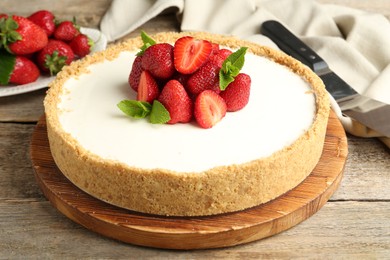 Photo of Tasty cheesecake with strawberries and mint on wooden table, closeup