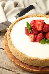 Photo of Tasty cheesecake with strawberries and mint on wooden table, closeup