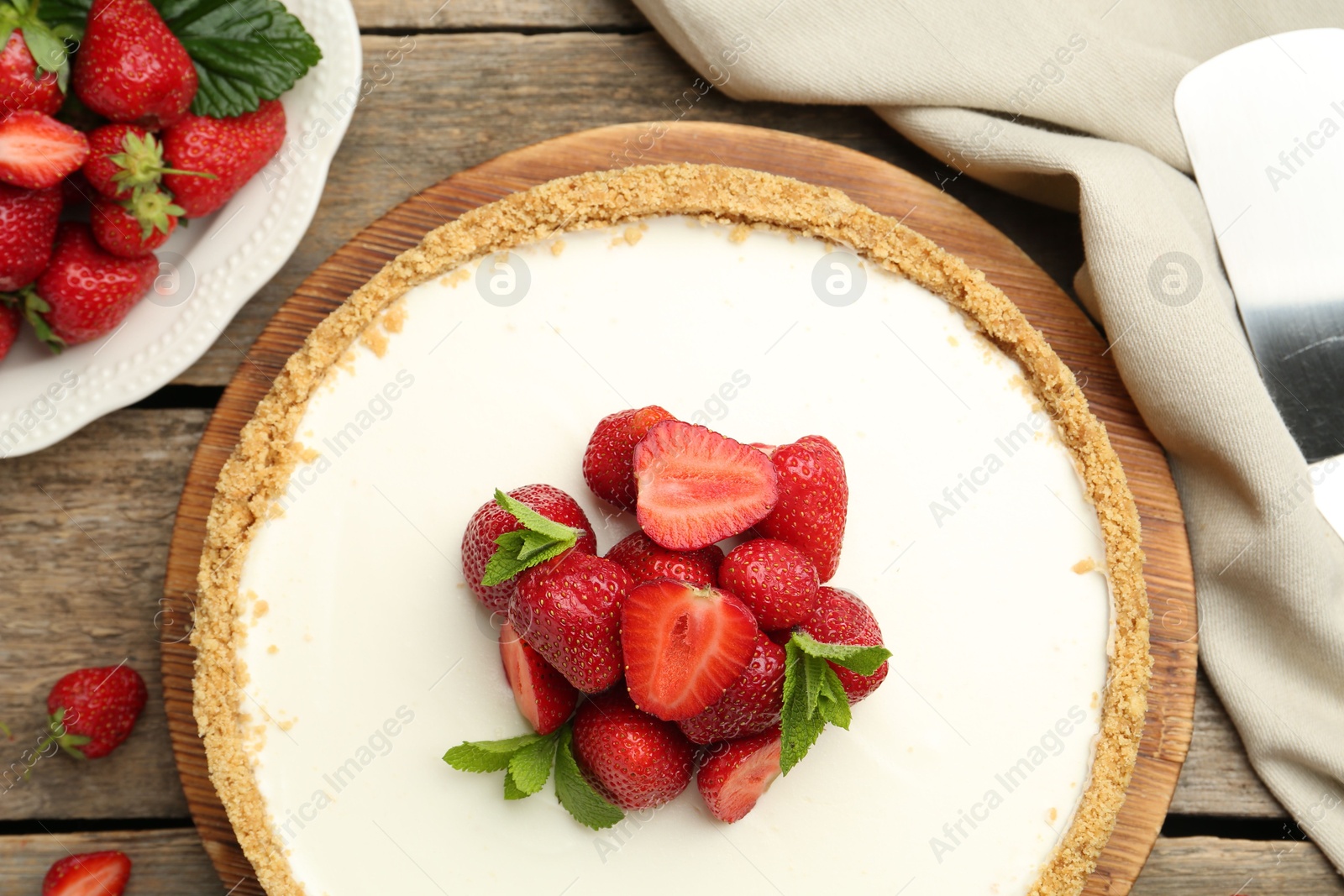Photo of Tasty cheesecake with strawberries and mint on wooden table, flat lay
