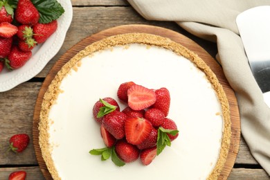 Photo of Tasty cheesecake with strawberries and mint on wooden table, flat lay