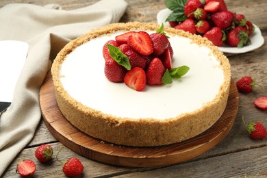 Photo of Tasty cheesecake with strawberries and mint on wooden table, closeup