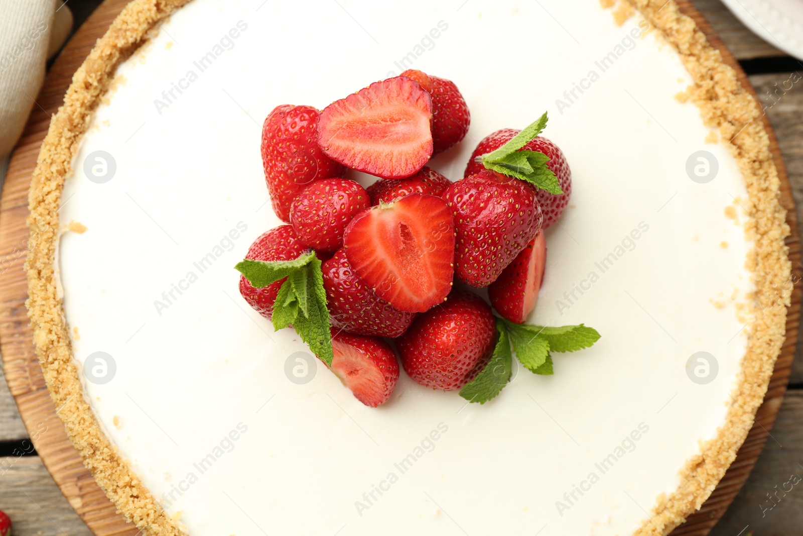 Photo of Tasty cheesecake with strawberries and mint on wooden table, top view