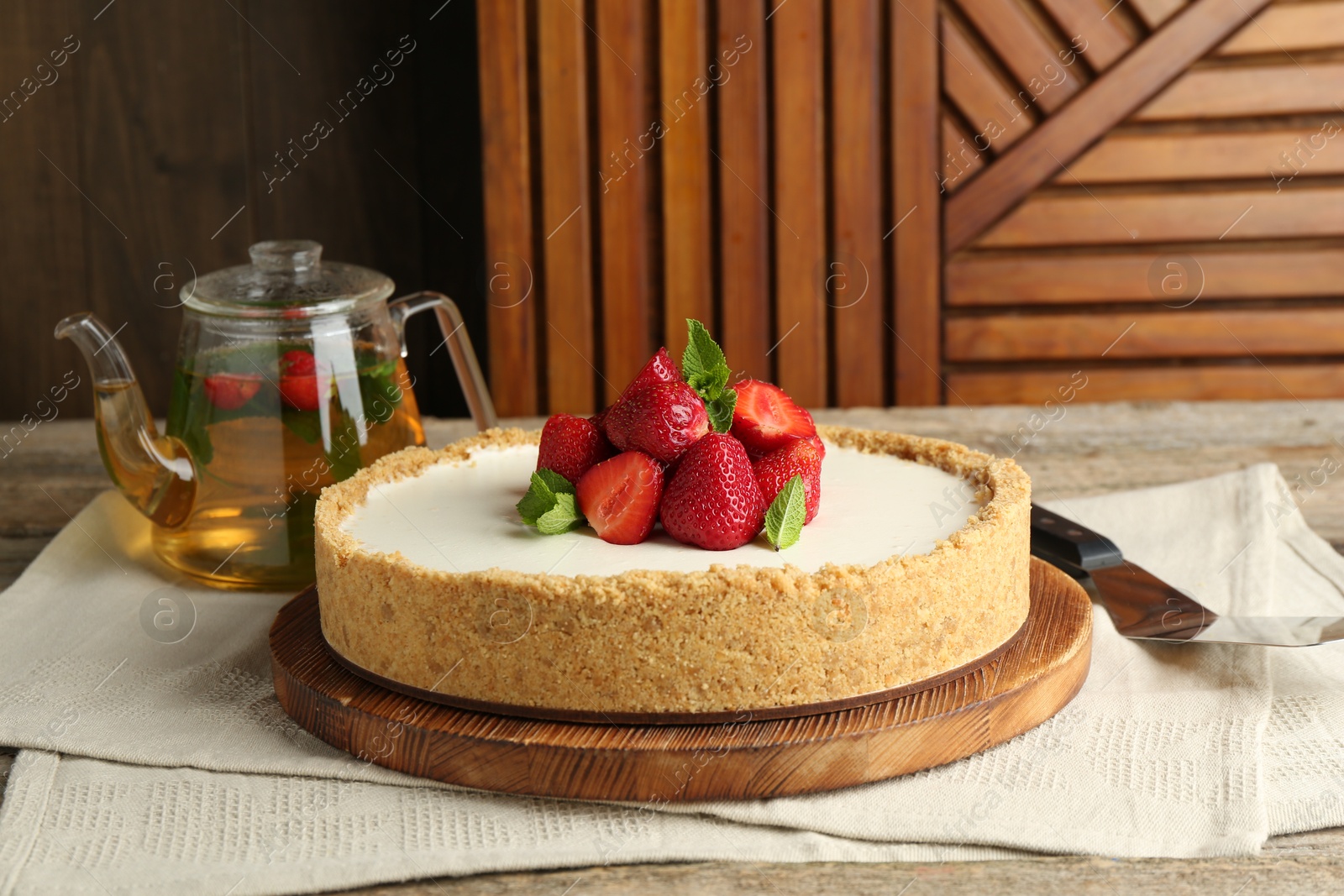 Photo of Tasty cheesecake with strawberries and mint on wooden table, closeup