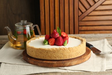 Photo of Tasty cheesecake with strawberries and mint on wooden table, closeup