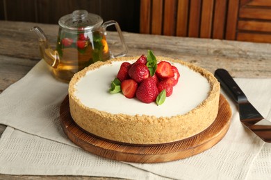 Photo of Tasty cheesecake with strawberries and mint on wooden table, closeup