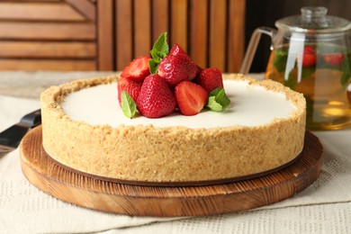 Photo of Tasty cheesecake with strawberries and mint on table against wooden background, closeup