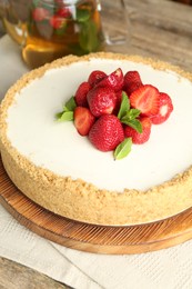 Photo of Tasty cheesecake with strawberries and mint on wooden table, closeup
