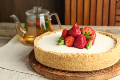 Photo of Tasty cheesecake with strawberries and mint on wooden table, closeup