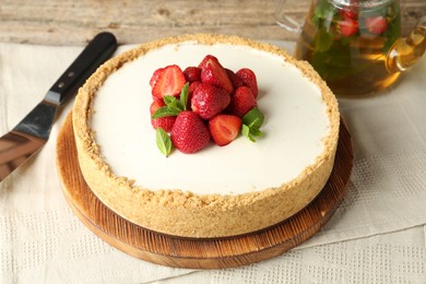 Photo of Tasty cheesecake with strawberries and mint on wooden table, closeup