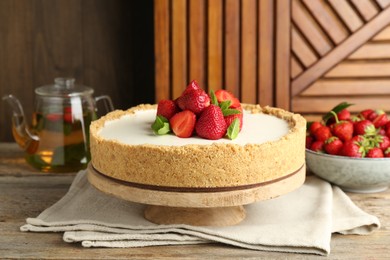 Photo of Tasty cheesecake with strawberries and mint on wooden table, closeup