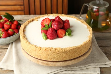 Photo of Tasty cheesecake with strawberries and mint on wooden table, closeup