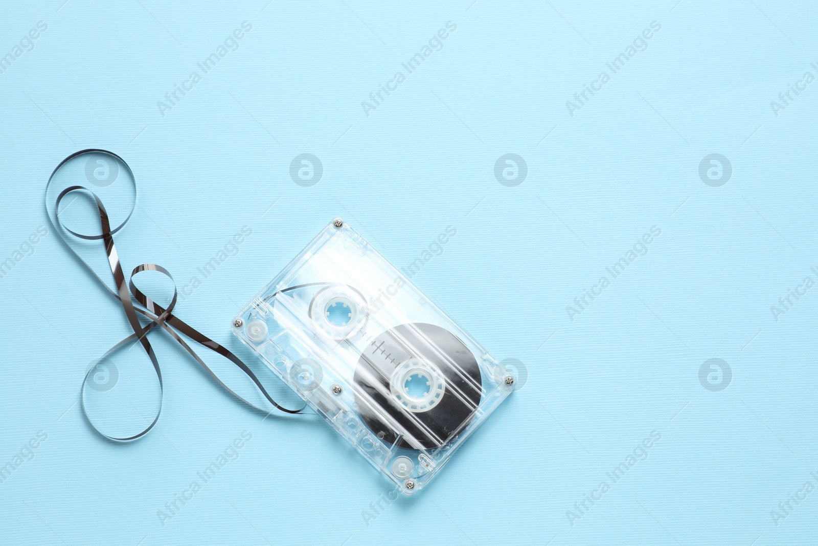 One audio cassette with magnetic tape on light blue background, top view. Space for text Photo of One audio cassette with magnetic tape on light blue background, top view. Space for text