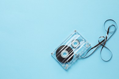 Photo of One audio cassette with magnetic tape on light blue background, top view. Space for text