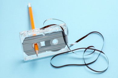Photo of Rewinding audio cassette with pencil on light blue background