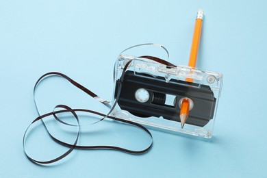 Photo of Rewinding audio cassette with pencil on light blue background