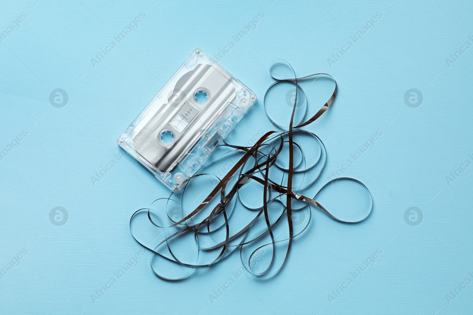 One audio cassette with magnetic tape on light blue background, top view Photo of One audio cassette with magnetic tape on light blue background, top view