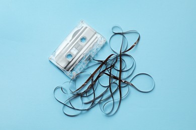 Photo of One audio cassette with magnetic tape on light blue background, top view