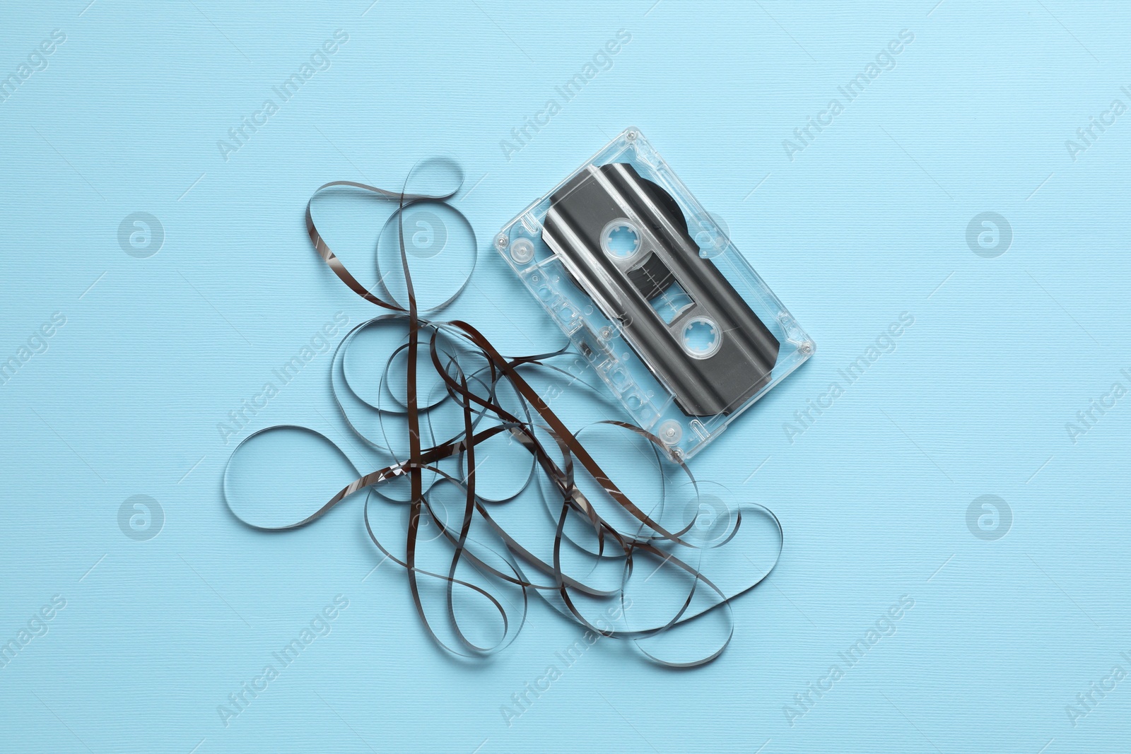 One audio cassette with magnetic tape on light blue background, top view Photo of One audio cassette with magnetic tape on light blue background, top view