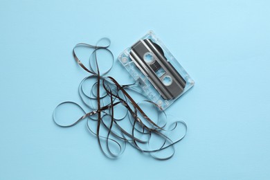 Photo of One audio cassette with magnetic tape on light blue background, top view