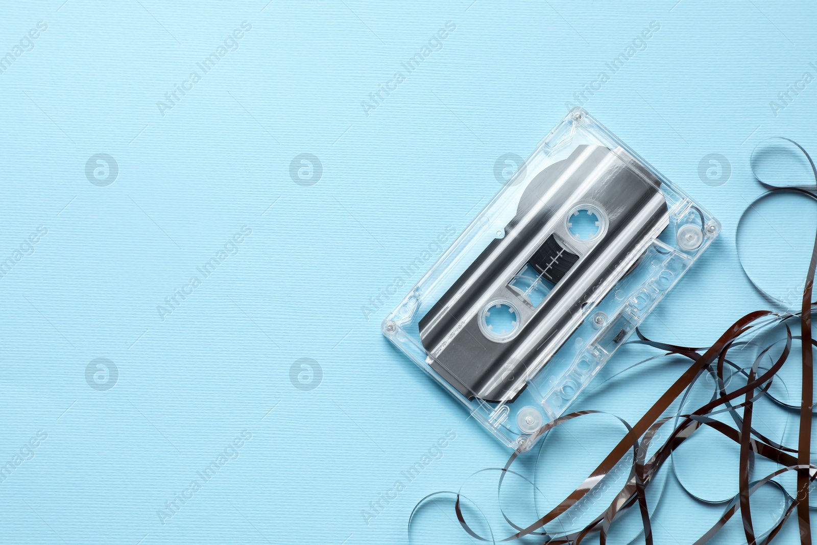 One audio cassette with magnetic tape on light blue background, top view. Space for text Photo of One audio cassette with magnetic tape on light blue background, top view. Space for text