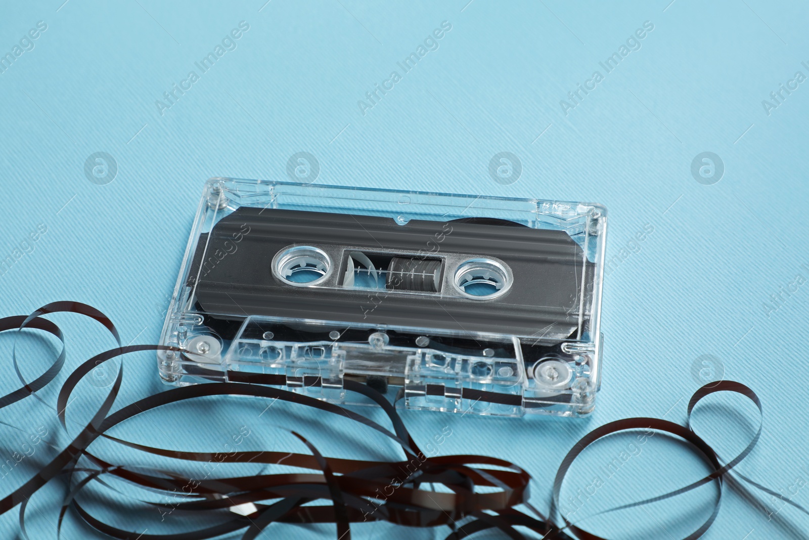 One audio cassette with magnetic tape on light blue background, closeup Photo of One audio cassette with magnetic tape on light blue background, closeup