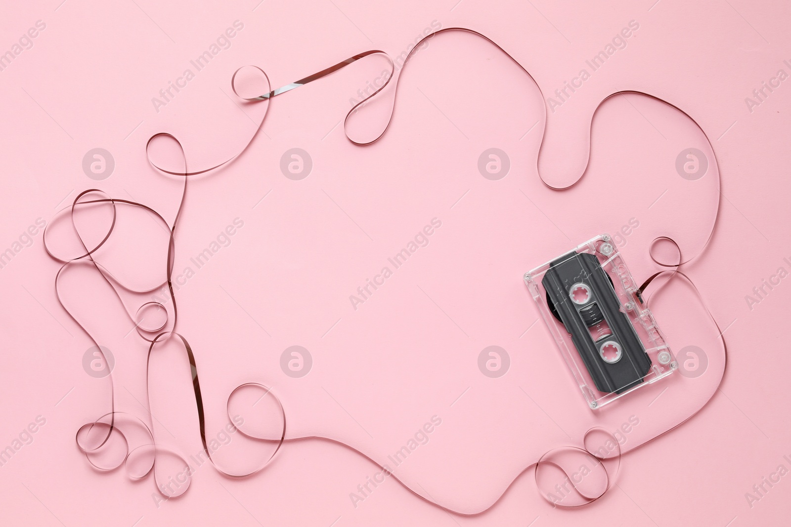 Frame made of magnetic tape from audio cassette on pink background, top view. Space for text Photo of Frame made of magnetic tape from audio cassette on pink background, top view. Space for text