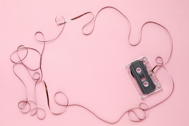 Photo of Frame made of magnetic tape from audio cassette on pink background, top view. Space for text