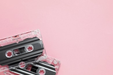 Photo of Audio cassettes with magnetic tapes on pink background, flat lay. Space for text