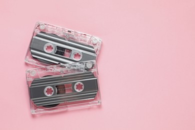 Photo of Audio cassettes with magnetic tapes on pink background, flat lay. Space for text