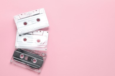 Photo of Audio cassettes with magnetic tapes on pink background, flat lay. Space for text
