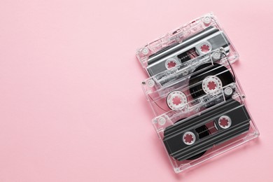Photo of Audio cassettes with magnetic tapes on pink background, flat lay. Space for text
