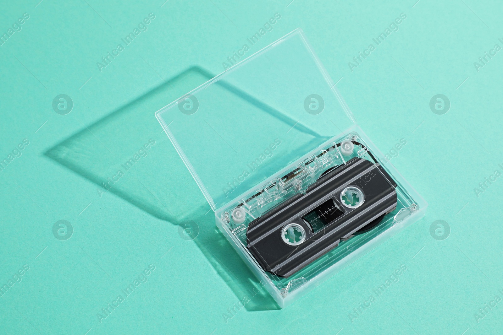 One audio cassette in open box on turquoise background, above view Photo of One audio cassette in open box on turquoise background, above view