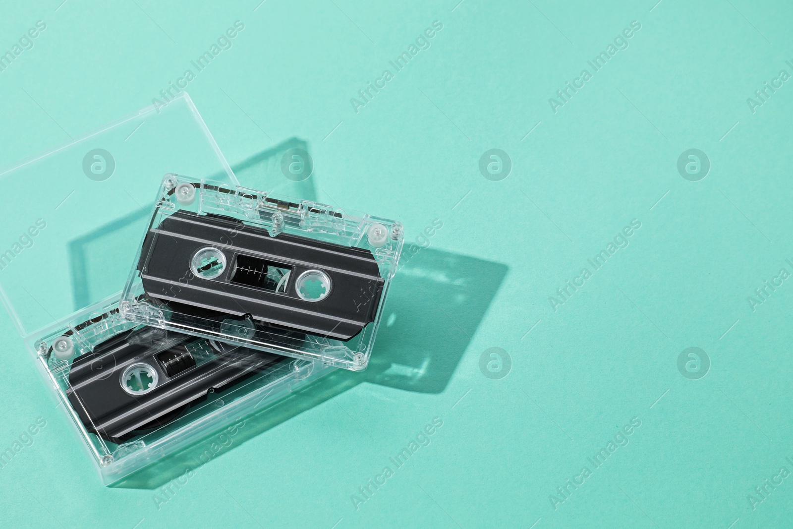 Audio cassettes with magnetic tapes on turquoise background, above view. Space for text Photo of Audio cassettes with magnetic tapes on turquoise background, above view. Space for text