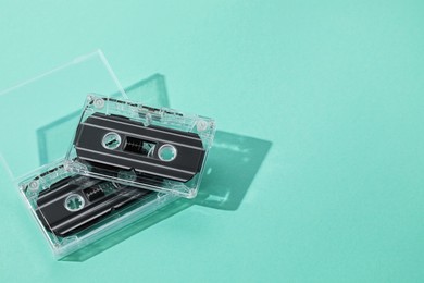 Photo of Audio cassettes with magnetic tapes on turquoise background, above view. Space for text