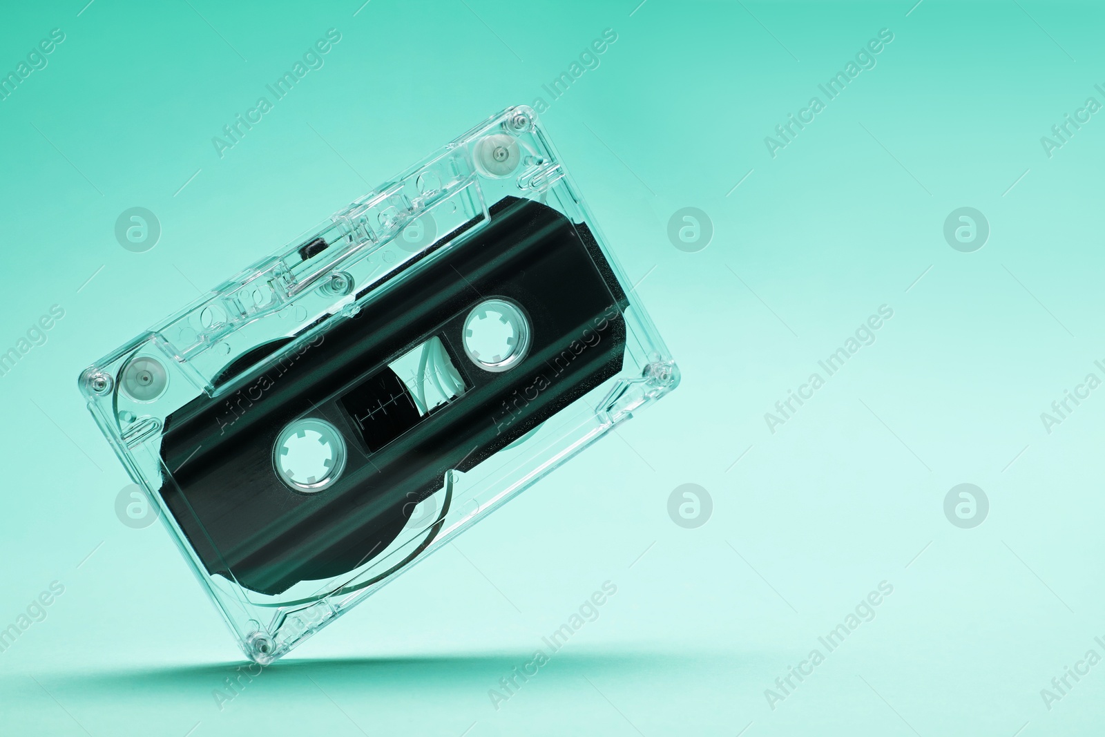 One audio cassette in air on turquoise background, closeup. Space for text Photo of One audio cassette in air on turquoise background, closeup. Space for text